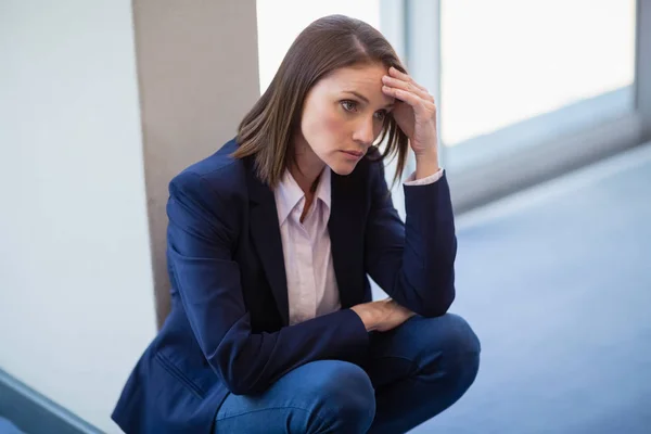 Bezorgd zakenvrouw crouching op verdieping — Stockfoto