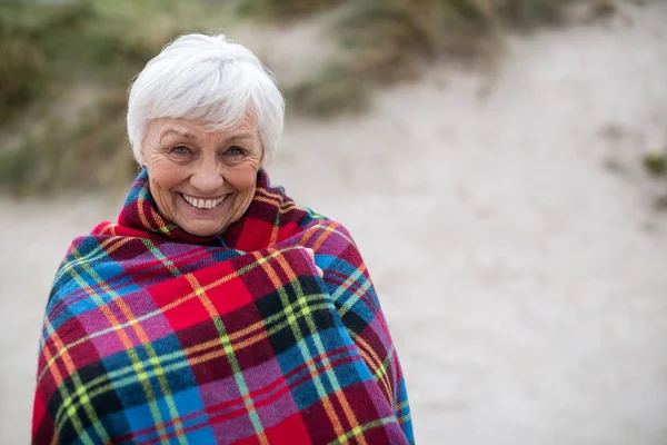 Retrato de mujer mayor envuelta en chal en la playa — Foto de Stock