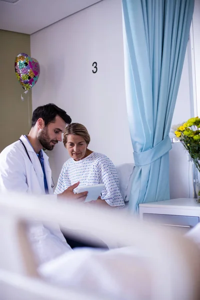 Male doctor interacting with female senior patient in the ward — Stock Photo, Image