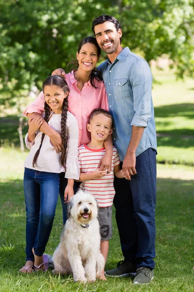 Портрет счастливой семьи с собакой, стоящей в парке — стоковое фото