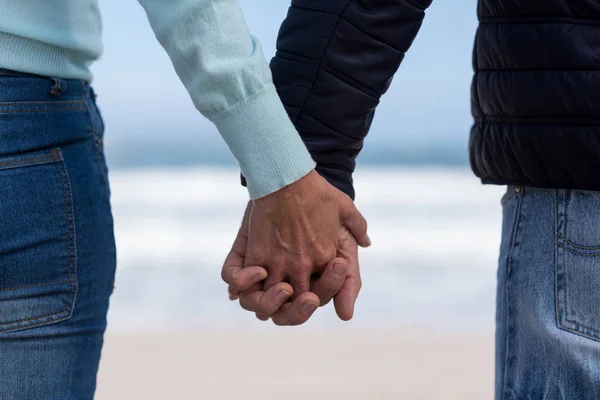 Пара стоящих и держащихся за руки на пляже — стоковое фото