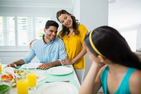 Dcera a rodiče mají jídlo na stole doma — Stock fotografie