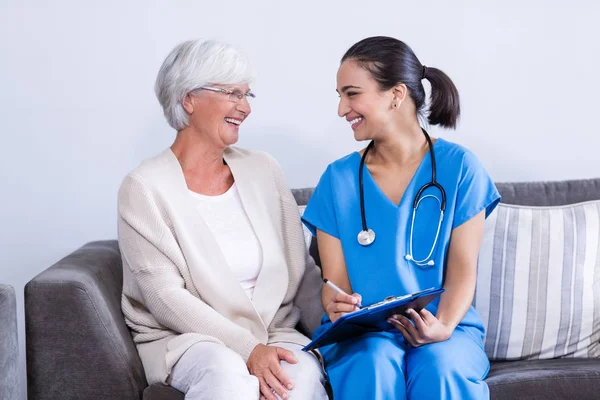 Medico e donna anziana discutono negli appunti — Foto Stock