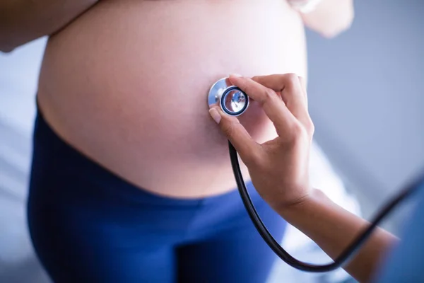 Mãos de médico examinando barriga de mulheres grávidas com estetoscópio — Fotografia de Stock