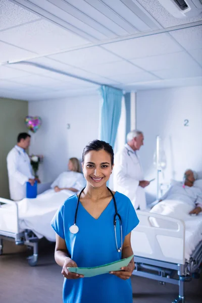 Médica sorrindo enquanto segura um arquivo — Fotografia de Stock