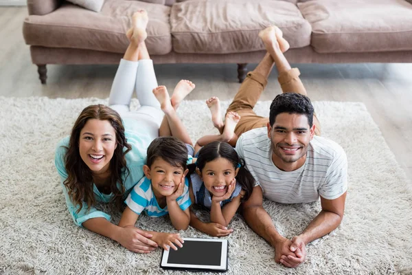 Портрет родителей и детей, лежащих на ковре и использующих цифровые планшеты — стоковое фото
