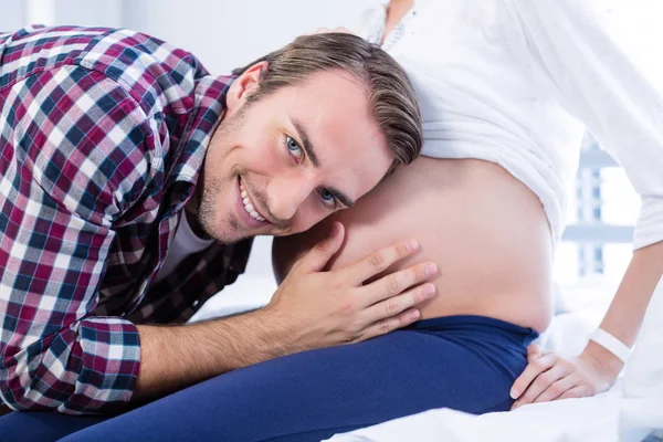 Usmívající se muž poslouchá těhotných ženách břicho v oddělení — Stock fotografie