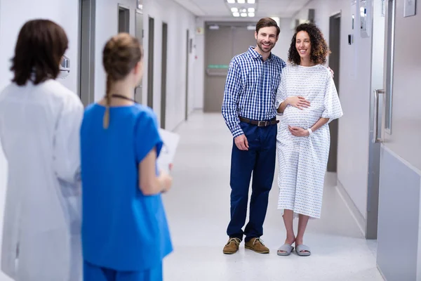 Pareja feliz interactuando con los médicos en el pasillo — Foto de Stock