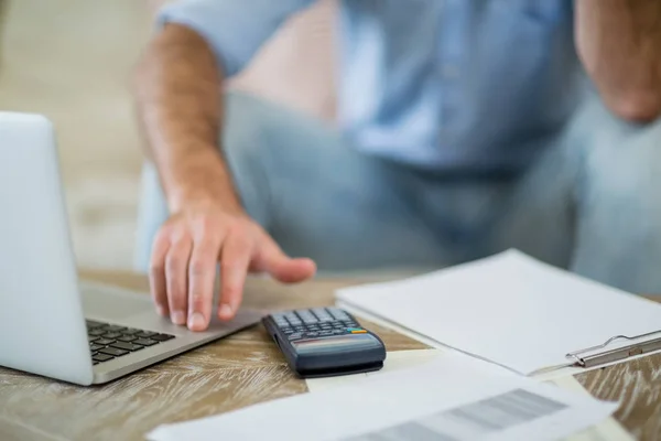 Mann benutzt Laptop mit Geldscheinen auf Wohnzimmertisch — Stockfoto