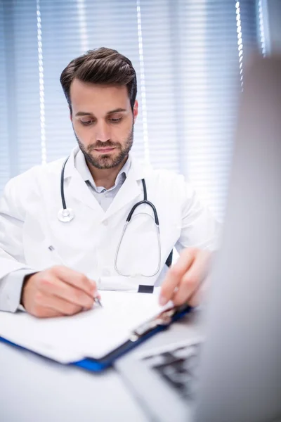 Mannelijke arts schrijven op Klembord — Stockfoto