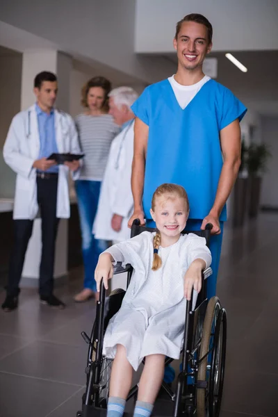 Doctor pushing disable girl in hospital corridor — Stock Photo, Image