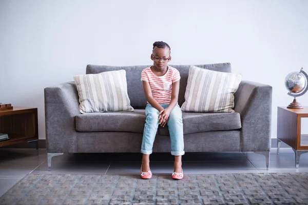 Расстроенная девушка сидит на диване в коридоре — стоковое фото