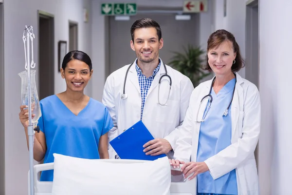 Porträt von Ärzten und Krankenschwester, die zusammen am Krankenhausbett stehen — Stockfoto