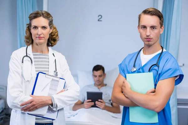 Lekarze, stojąc z raportów i pacjenta przy użyciu cyfrowego tabletu w tle — Zdjęcie stockowe