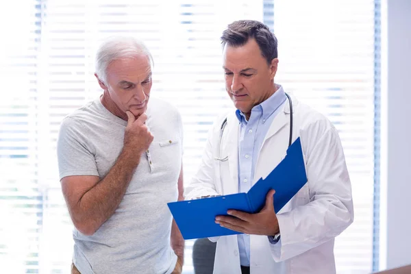 Arzt und Senior diskutieren über Akten — Stockfoto