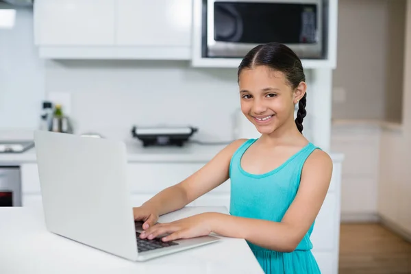 Chica usando el ordenador portátil en la cocina en casa —  Fotos de Stock