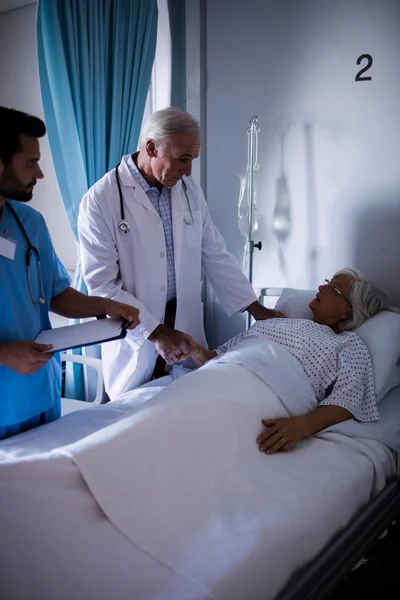 Médecins réconfortant patient âgé sur le lit — Photo