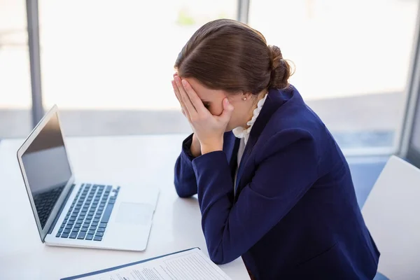 Empresária cansada sentada na mesa com laptop — Fotografia de Stock