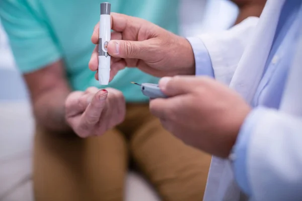 Mid section of doctor examining senior patient blood sugar — Stock Photo, Image