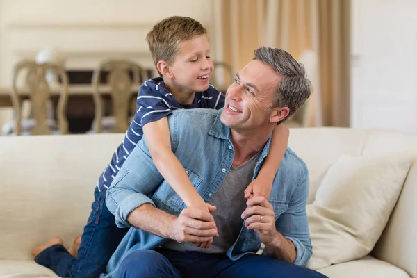 Usmívající se syn všeobjímající otce v obývacím pokoji — Stock fotografie