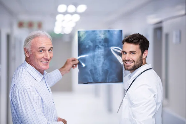 Портрет врача и пациента, держащего рентген в коридоре — стоковое фото
