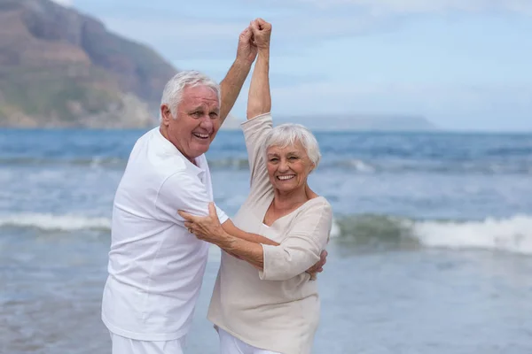 Старшая пара веселится вместе на пляже — стоковое фото