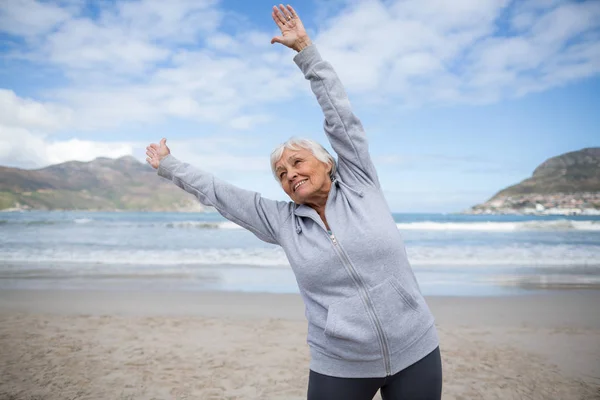 Ανώτερος γυναίκα κάνει το τέντωμα άσκηση στην παραλία — Φωτογραφία Αρχείου