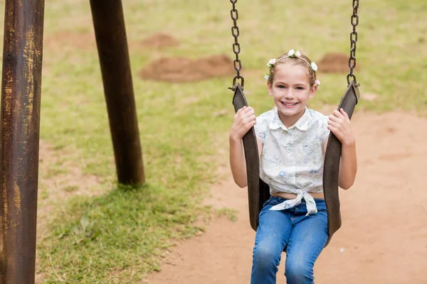 Mutlu kız parkta bir salıncak üzerinde oturan — Stok fotoğraf