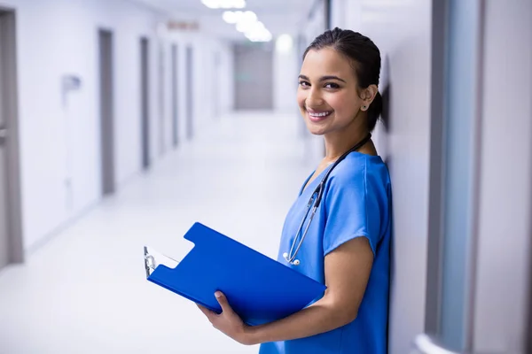 Retrato de uma médica segurando o arquivo no corredor — Fotografia de Stock