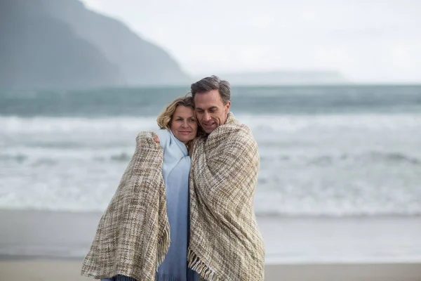Зріла пара, загорнута в ковдру на пляжі — стокове фото