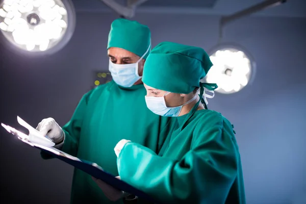 Male and female surgeon checking the medical report of the patient — Stock Photo, Image