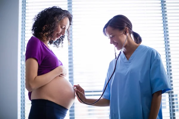 Arzt untersucht Schwangerschaftsbauch mit Stethoskop auf Station — Stockfoto