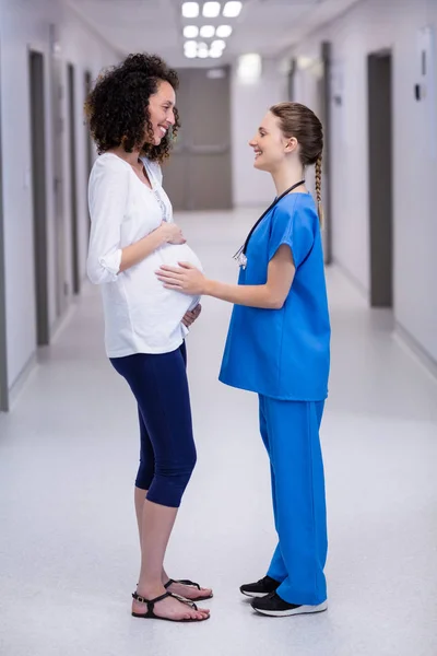 Medico e donna incinta che interagiscono in corridoio — Foto Stock