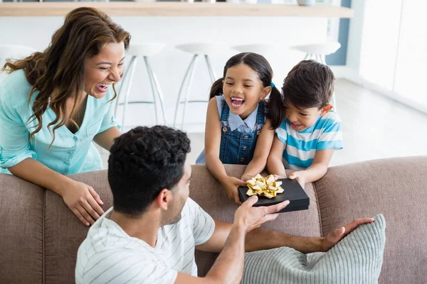 Padre recibiendo un regalo de sus hijos y esposa en la sala de estar — Foto de Stock