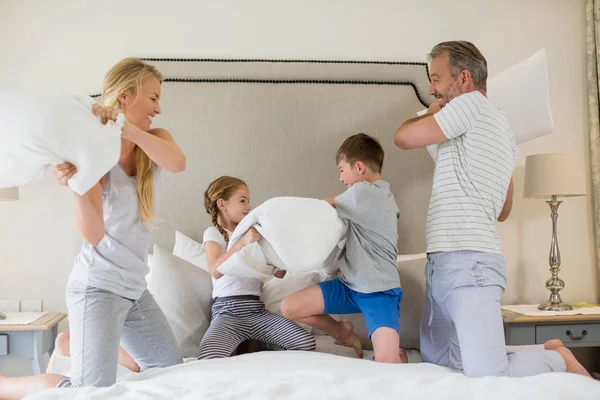 Linda familia teniendo una pelea de almohadas en el dormitorio — Foto de Stock