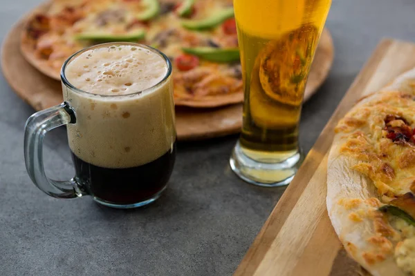 Una taza de cerveza y un vaso con pizza en el fondo — Foto de Stock