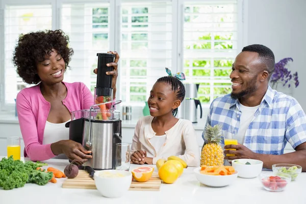 Sorrindo pais e filha preparando smoothie de morango na cozinha — Fotografia de Stock