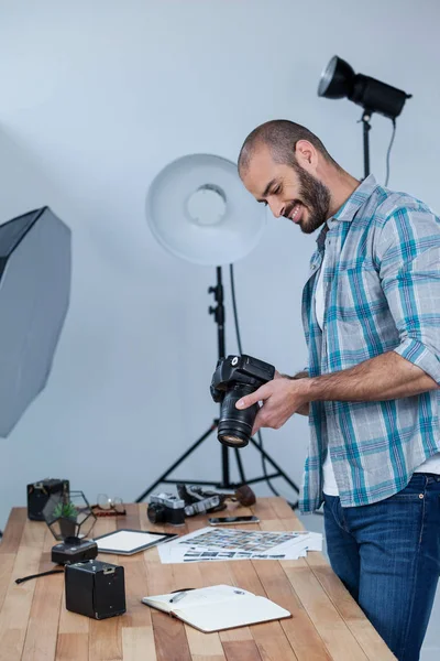 Fotógrafo masculino revisando fotos capturadas en su cámara digital —  Fotos de Stock