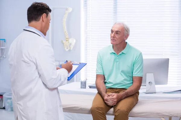 Doctor escribiendo en portapapeles en la clínica — Foto de Stock