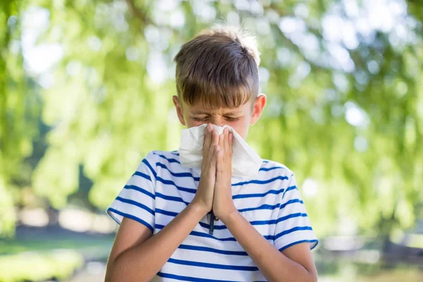 Rapaz a limpar o nariz enquanto espirra — Fotografia de Stock