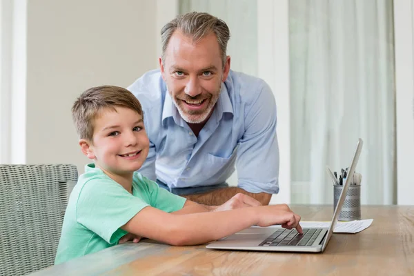 Vader en zoon met behulp van laptop aan balie — Stockfoto