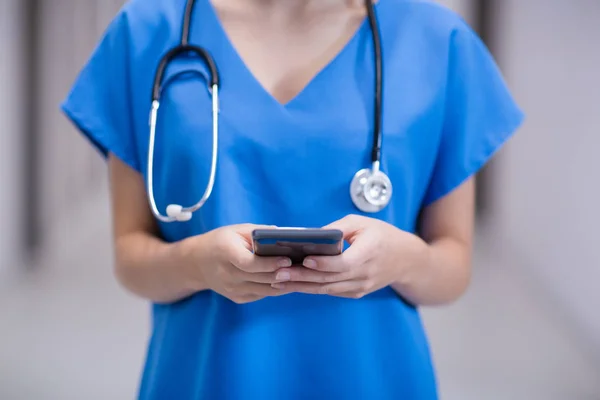 Mid sectie van vrouwelijke arts met behulp van mobiele telefoon in gang — Stockfoto