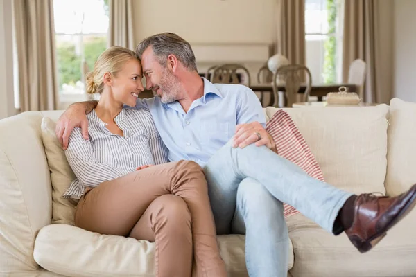 Romantický pár sedí na pohovce s rukou kolem v obývacím pokoji — Stock fotografie