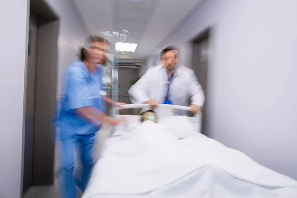 Médecins poussant lit civière d'urgence dans le couloir — Photo