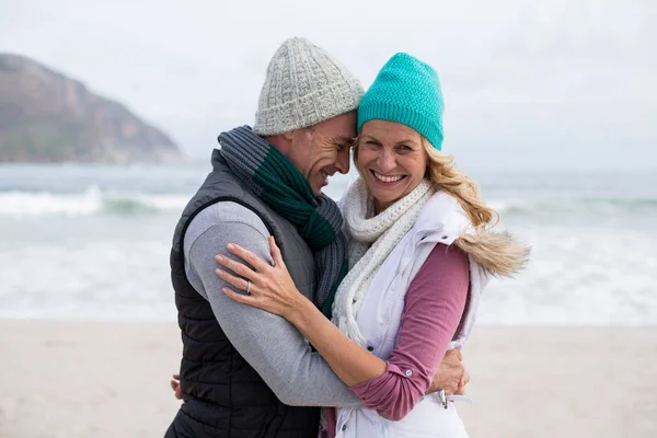 Äldre par omfamnar varandra på stranden — Stockfoto