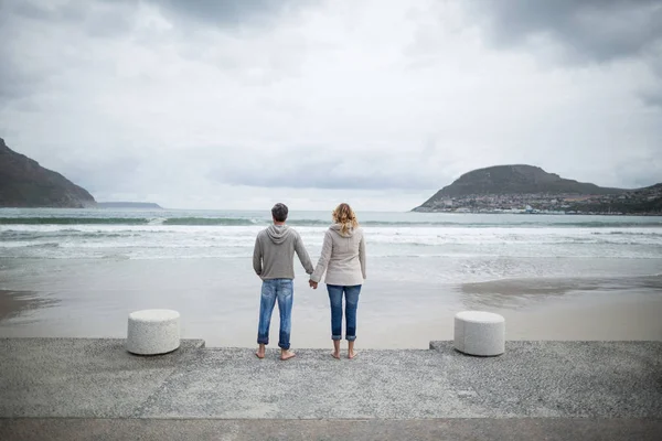 情侣站在一起手牵着手在海滩上 — 图库照片