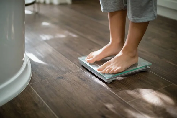 Boy checking his weight on weight scale — Stock Photo, Image