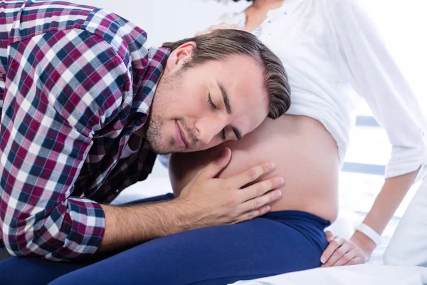 Man lyssnar på gravid kvinnas mage i församling — Stockfoto