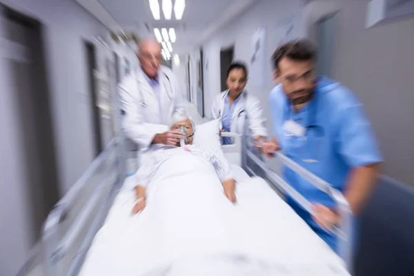 Medico e infermiere spingendo letto barella di emergenza in corridoio — Foto Stock