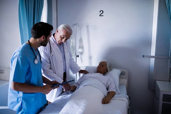 Läkare tröstande senior patienten på säng — Stockfoto